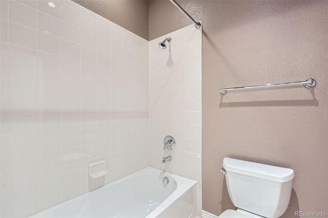 bathroom featuring tiled shower / bath combo and toilet