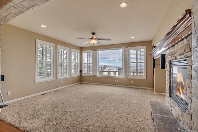 unfurnished living room with plenty of natural light, ceiling fan, carpet floors, and a fireplace