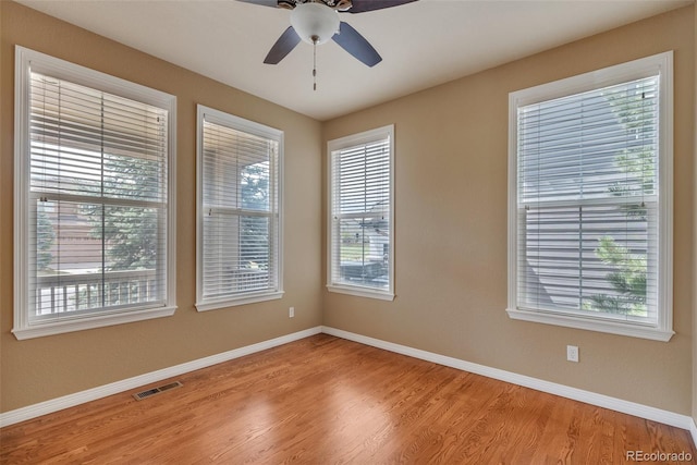 spare room featuring a ceiling fan, baseboards, visible vents, and light wood-style flooring