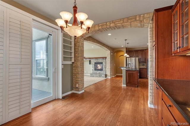 corridor with an inviting chandelier, arched walkways, light wood finished floors, and recessed lighting