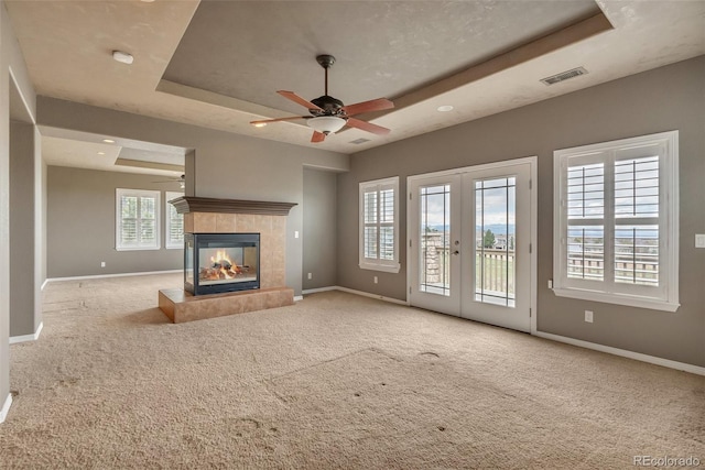 unfurnished living room with a ceiling fan, baseboards, visible vents, and a raised ceiling