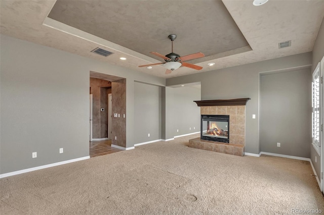 unfurnished living room featuring carpet flooring, a ceiling fan, baseboards, a tray ceiling, and visible vents