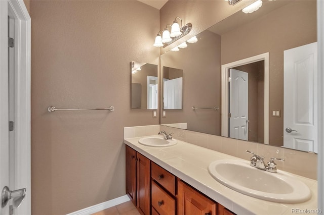 bathroom featuring double vanity, baseboards, a sink, and tile patterned flooring