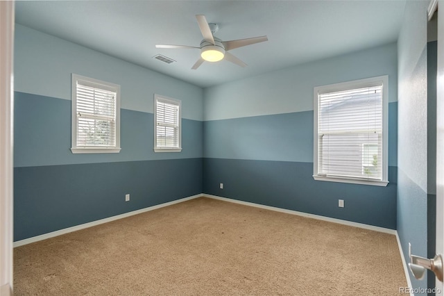 spare room featuring carpet floors, baseboards, ceiling fan, and visible vents