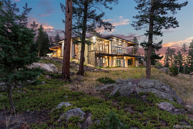 back house at dusk featuring a balcony