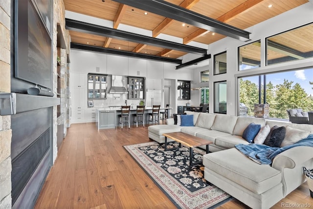 living room with a towering ceiling, wood ceiling, beam ceiling, and light hardwood / wood-style floors