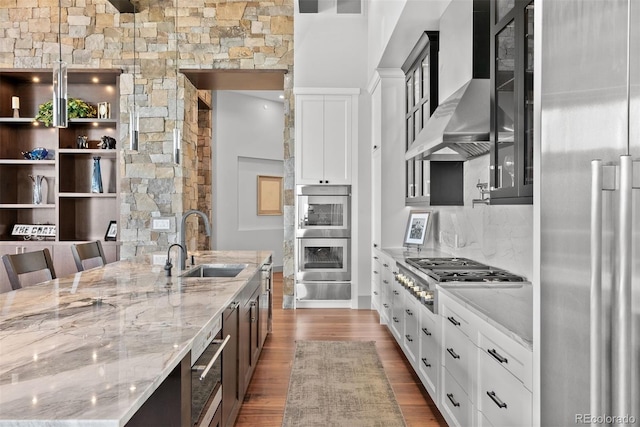 kitchen featuring white cabinets, stainless steel appliances, wall chimney exhaust hood, and hardwood / wood-style floors