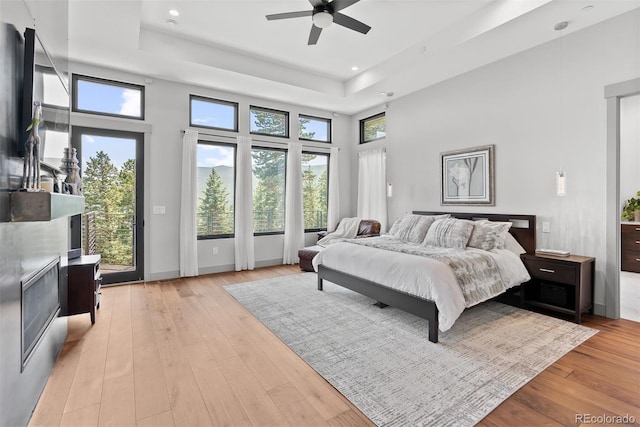 bedroom with a raised ceiling, a towering ceiling, ceiling fan, and light hardwood / wood-style flooring