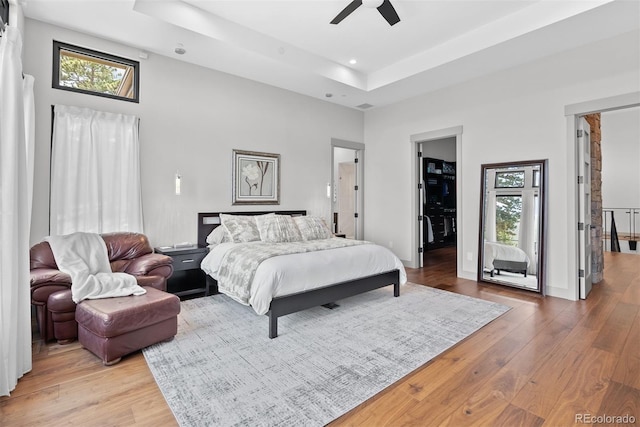 bedroom with wood-type flooring, a closet, a towering ceiling, a spacious closet, and ceiling fan