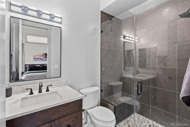 bathroom featuring a shower with shower door, vanity, and toilet