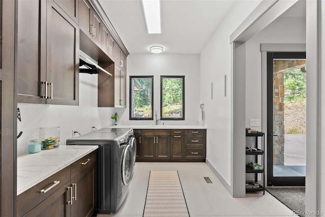 clothes washing area with a skylight, cabinets, independent washer and dryer, and a healthy amount of sunlight