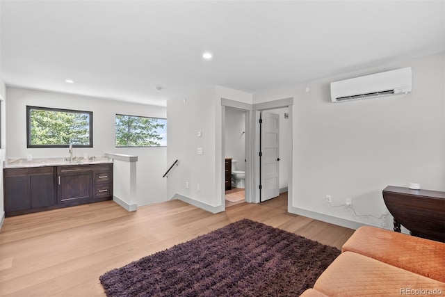 living room featuring light hardwood / wood-style floors, sink, and a wall mounted air conditioner