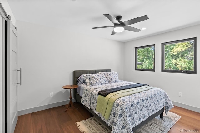 bedroom featuring ceiling fan, hardwood / wood-style flooring, and a barn door