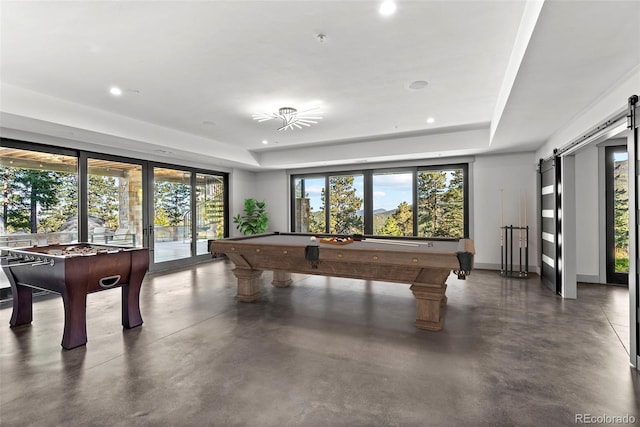 recreation room with pool table, a tray ceiling, and a barn door