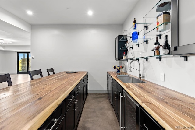 kitchen featuring butcher block countertops, sink, concrete flooring, and beverage cooler