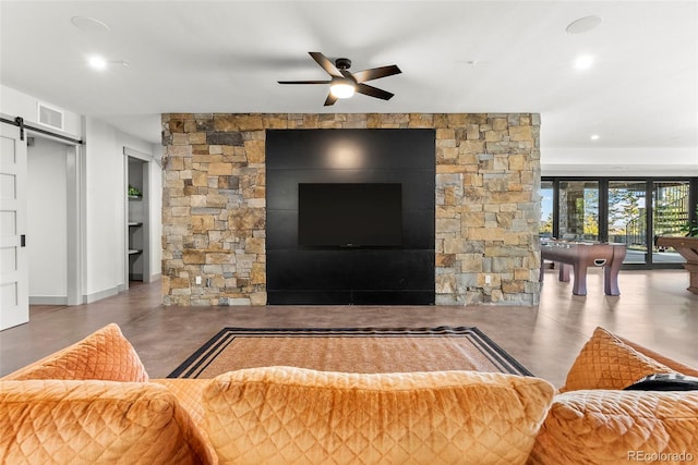 living room with ceiling fan, a barn door, and concrete flooring