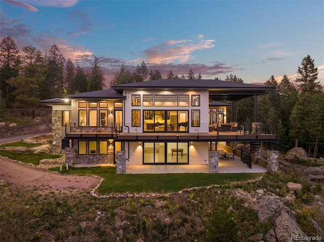 back house at dusk featuring a balcony, a yard, and a patio area