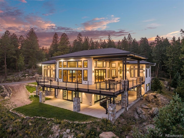 back house at dusk featuring a patio area and a yard