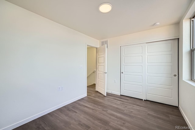 unfurnished bedroom featuring dark hardwood / wood-style flooring and a closet