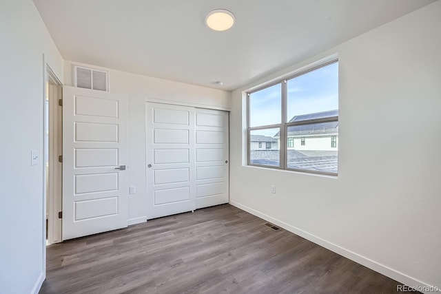 unfurnished bedroom featuring visible vents, baseboards, and wood finished floors