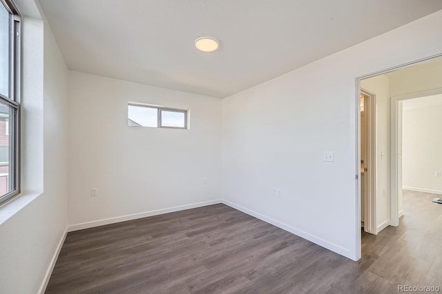 unfurnished room with dark wood finished floors and baseboards