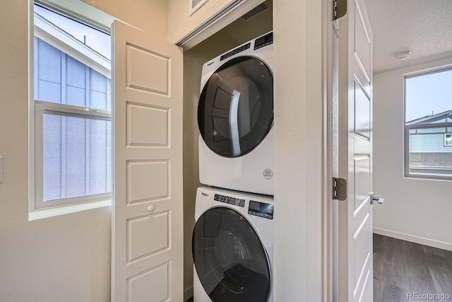 laundry room featuring baseboards, laundry area, stacked washing maching and dryer, dark wood-style floors, and a textured ceiling