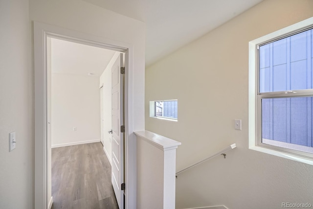 corridor with an upstairs landing, baseboards, and wood finished floors