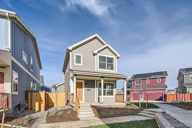 view of front of house featuring covered porch, a garage, and solar panels