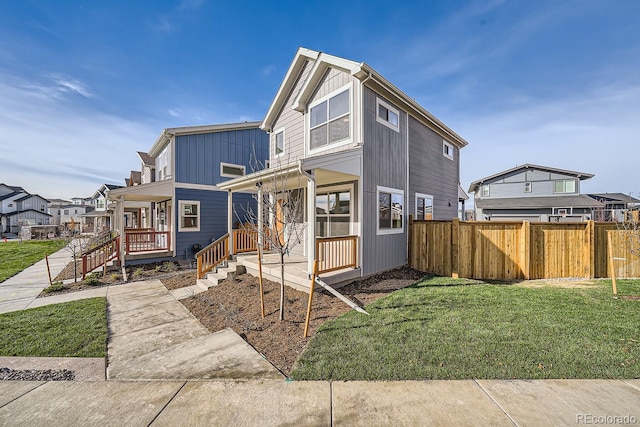 view of front of home featuring fence, a porch, a residential view, a front lawn, and board and batten siding