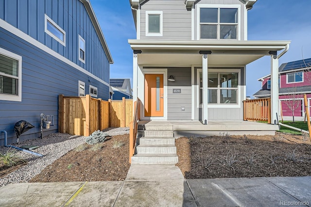 view of front facade with board and batten siding, a porch, and fence