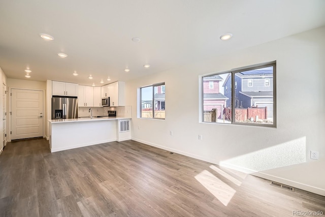 kitchen featuring a peninsula, stainless steel appliances, dark wood-type flooring, light countertops, and white cabinetry