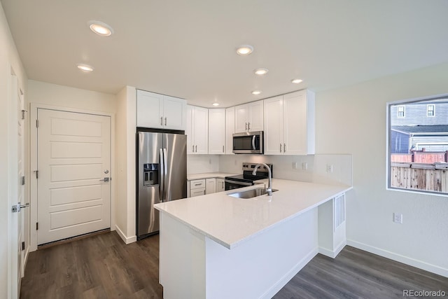 kitchen featuring light countertops, appliances with stainless steel finishes, a peninsula, white cabinets, and dark wood-style flooring