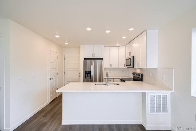 kitchen with kitchen peninsula, white cabinetry, sink, and stainless steel appliances