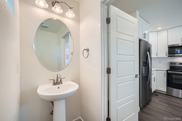 bathroom featuring wood finished floors, visible vents, and backsplash