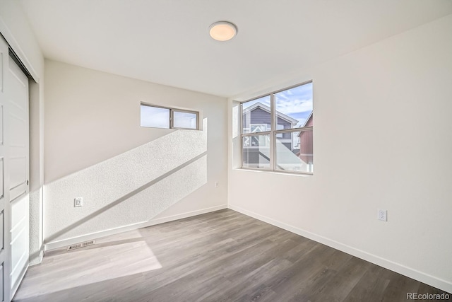 empty room with visible vents, baseboards, and wood finished floors