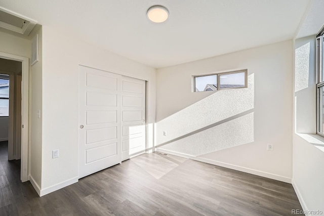 unfurnished bedroom with a closet, baseboards, and dark wood-style floors