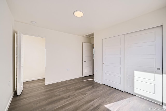 unfurnished bedroom featuring a closet, baseboards, and dark wood-style flooring