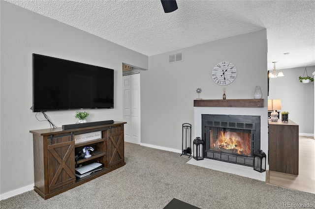 2185 Ambleside Dr, Colorado Springs, CO 80915 - carpeted living area featuring a fireplace with flush hearth, a textured ceiling, and baseboards