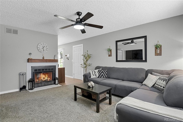 2185 Ambleside Dr, Colorado Springs, CO 80915 - living area with ceiling fan, a fireplace with flush hearth, a textured ceiling, carpet, and baseboards