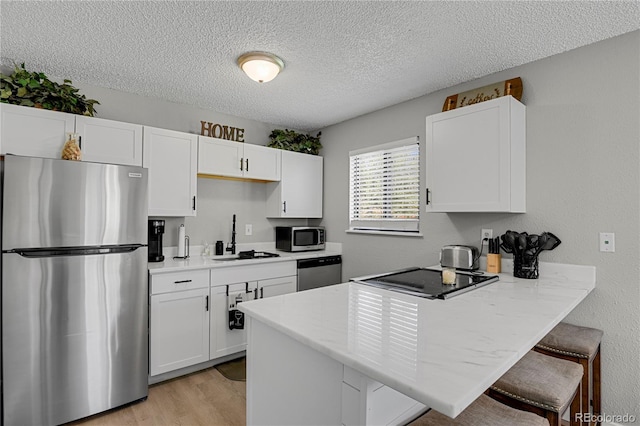 2185 Ambleside Dr, Colorado Springs, CO 80915 - kitchen featuring appliances with stainless steel finishes, a sink, a peninsula, a breakfast bar, and white cabinets