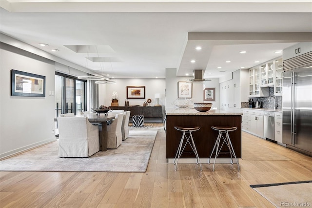 460 S Marion Pkwy Unit 1856, Denver, CO 80209 - kitchen with stainless steel appliances, a breakfast bar area, white cabinets, light wood-type flooring, and recessed lighting