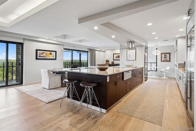 460 S Marion Pkwy Unit 1856, Denver, CO 80209 - kitchen featuring dark brown cabinetry, light wood-style floors, light stone counters, recessed lighting, and a breakfast bar area