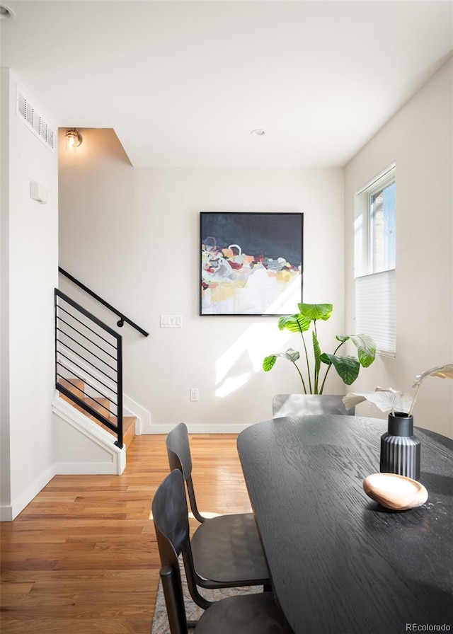 dining room featuring visible vents, stairs, baseboards, and wood finished floors