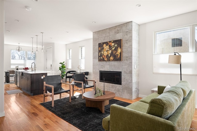 living room featuring baseboards, light wood-type flooring, a wealth of natural light, and a tile fireplace