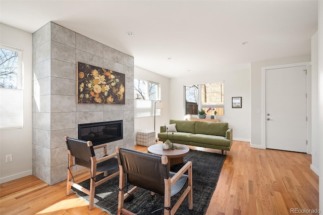 living area featuring a fireplace, baseboards, and light wood-style floors