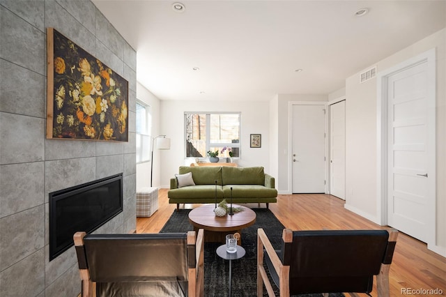 living room with wood finished floors, visible vents, baseboards, recessed lighting, and a fireplace