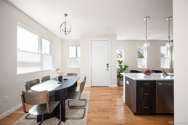 dining area with a chandelier, light wood-type flooring, and baseboards