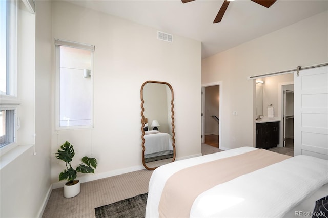 bedroom with visible vents, a sink, a barn door, connected bathroom, and baseboards