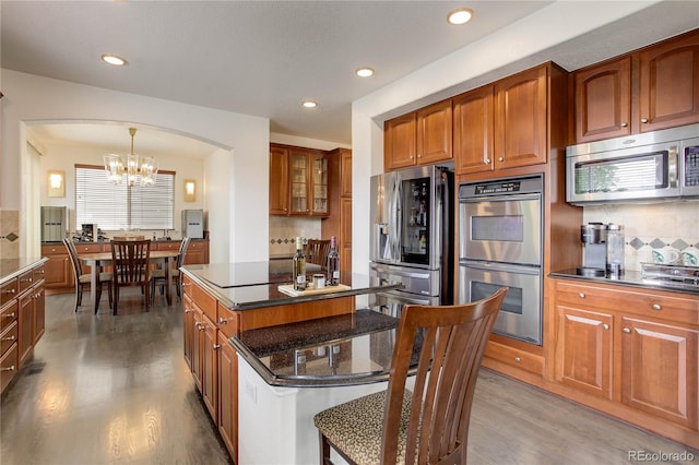 10609 Chadsworth Ln, Highlands Ranch, CO 80126 - kitchen with stainless steel appliances, arched walkways, a chandelier, light wood-style flooring, and brown cabinetry
