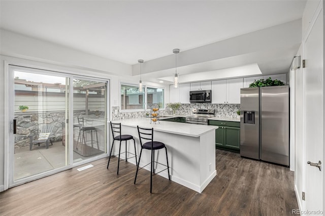 kitchen with dark wood-type flooring, stainless steel appliances, decorative backsplash, sink, and kitchen peninsula